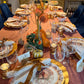 A Sophistiplate LLC Turkey & Gourds: Thanksgiving Table for 16 set on a mauve tablecloth with velvet ribbons, gourds, and floral centerpieces.