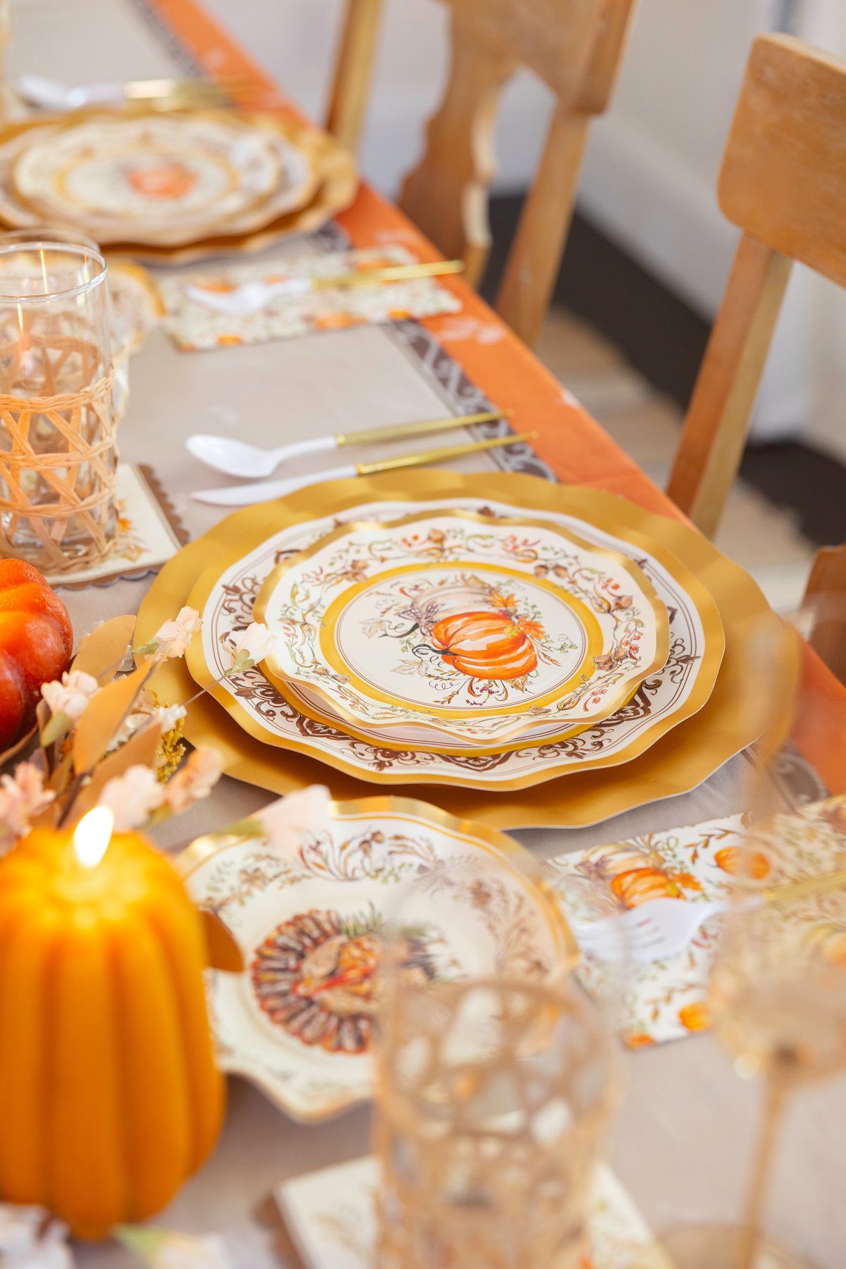 Create a festive autumn table with the Sophistiplate Turkey & Gourds Table Setting, featuring designer plates, gold utensils, elegant glassware, and pumpkin décor in warm orange, gold, and neutral tones.