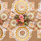 Holiday dinner table set with a plaid paper table runner, gold chargers and a floral centerpiece